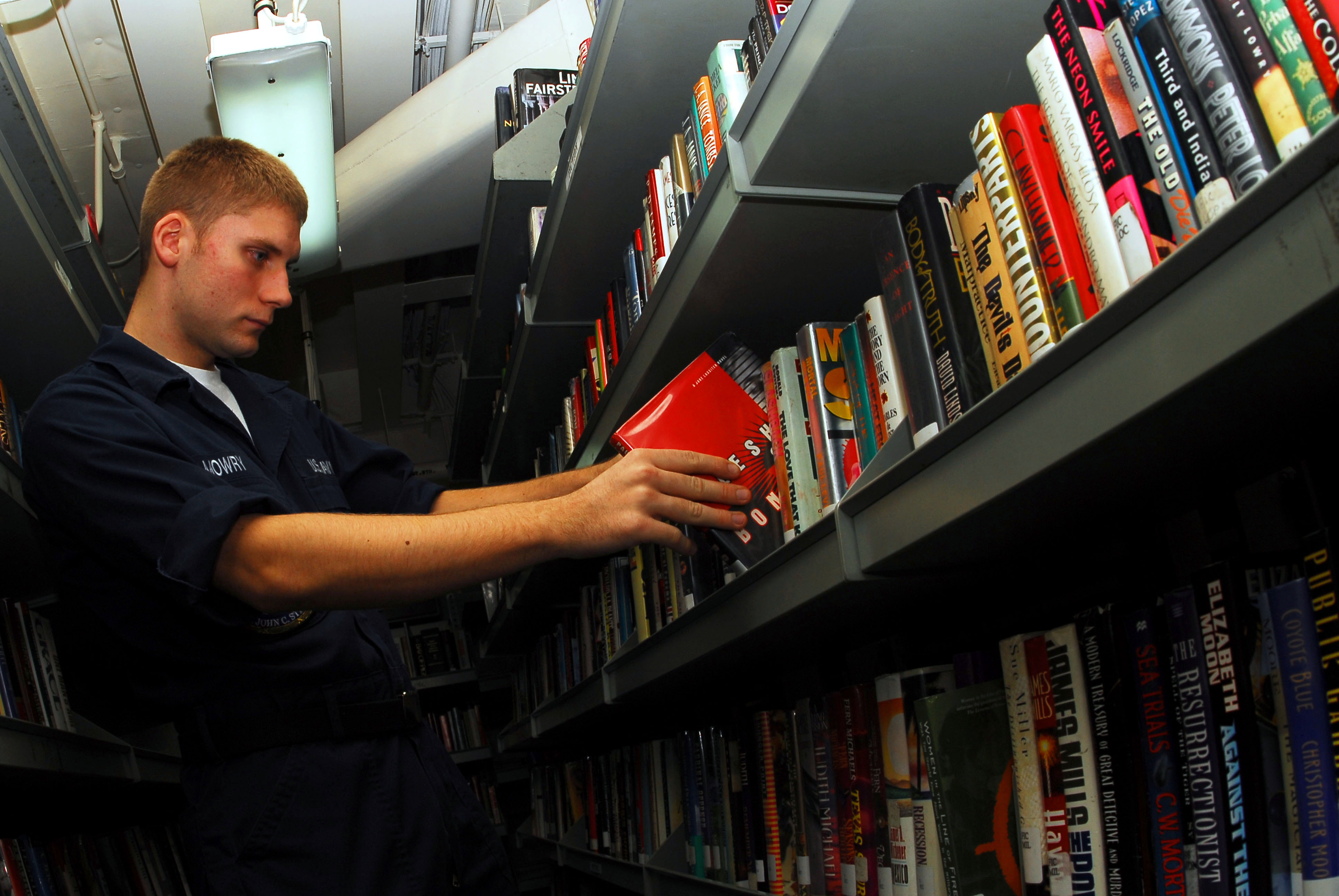 US Navy 070224-N-9928E-020 Airman Rick Mowry places books in back on shelves in the ship^rsquo,s library aboard Nimitz-class aircraft carrier USS John C. Stennis (CVN 74)