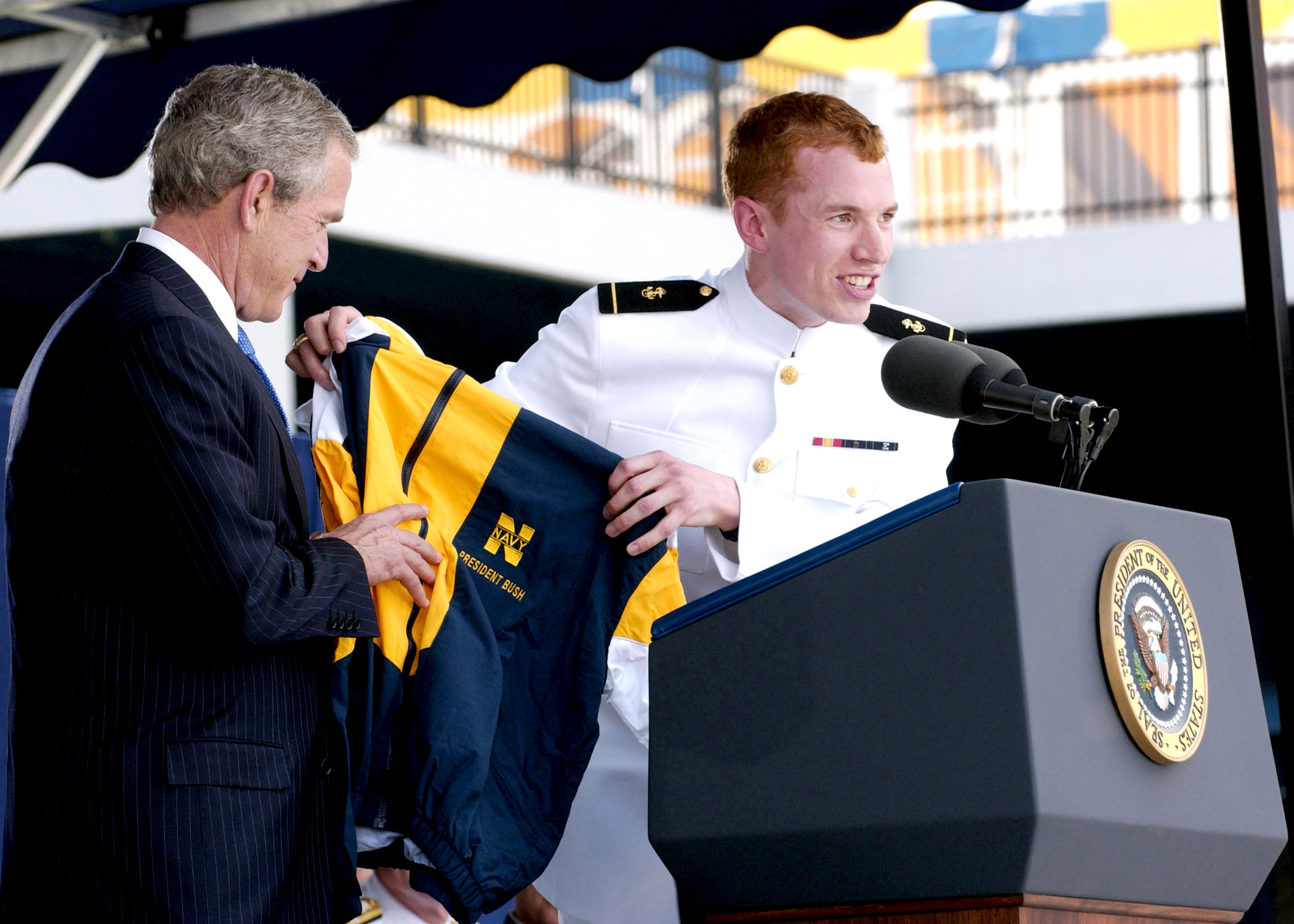 US Navy 050527-N-5390M-193 A graduating Midshipman presents U.S. President George W. Bush with a Naval Academy windbreaker jacket, during the 2005 Naval Academy Graduation Ceremony