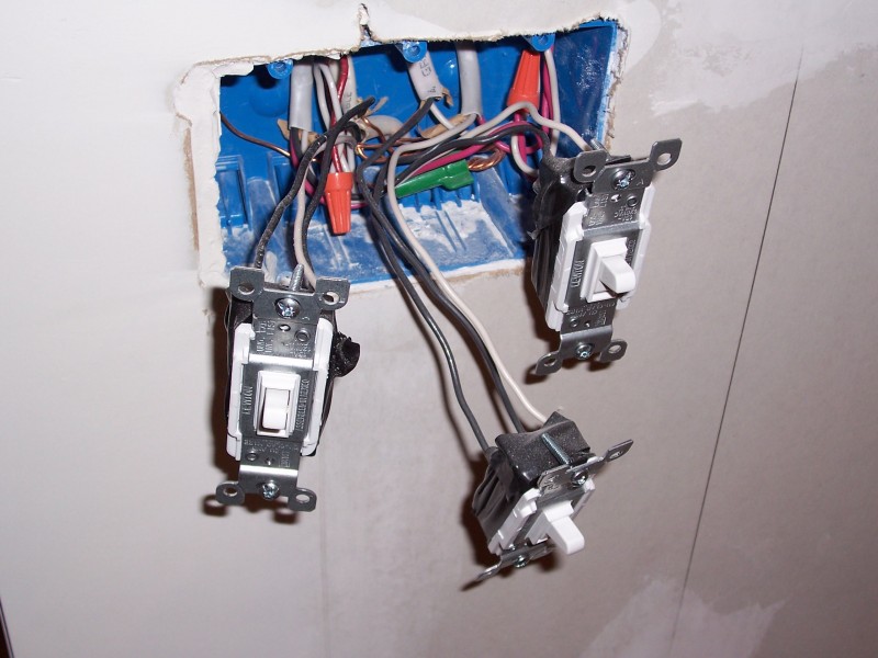 Three light switches with exposed wiring