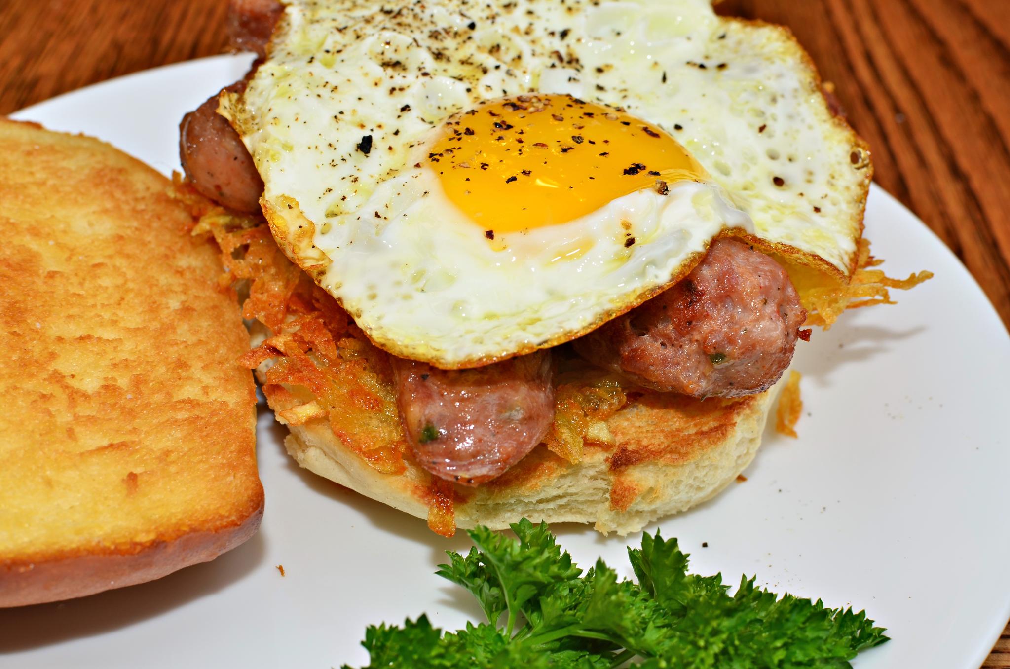 Mmm... fried egg, sliced sausage, and hash browns on a grilled bun (6226666569)