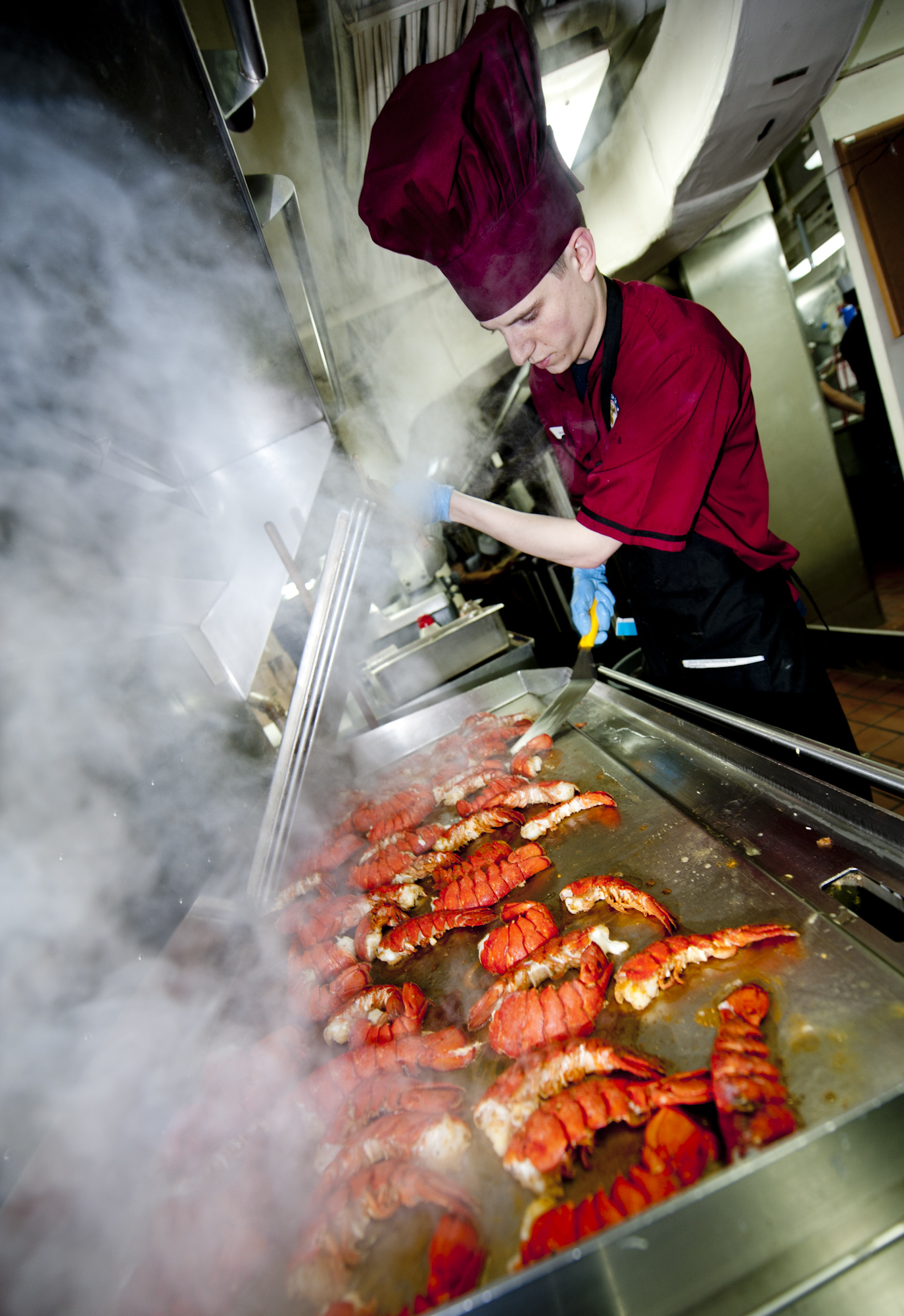 US Navy 111220-N-OY799-224 Culinary Specialist Seaman Jon Ketola grills lobster tails in preparation for the Christmas meal in the aft galley aboar