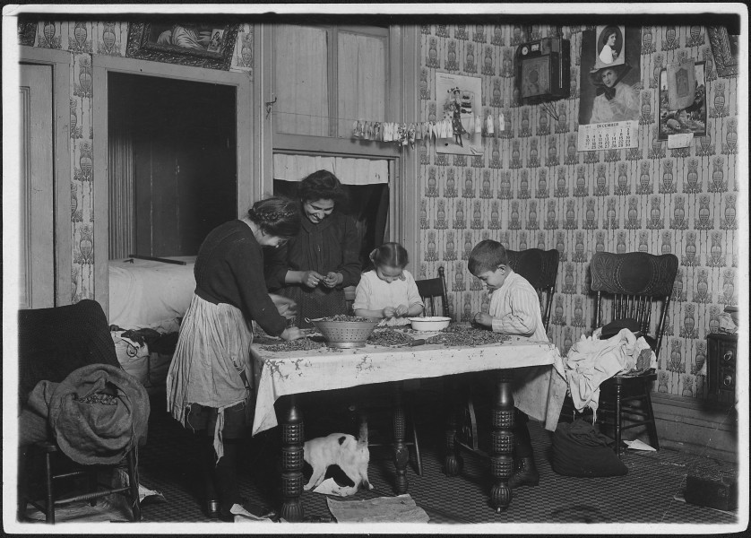 Mrs. Salvia, Joe, 10 years old, Josephine, 14 years, Camille, 7 years, picking nuts in a dirty tenement home. The bag... - NARA - 523490