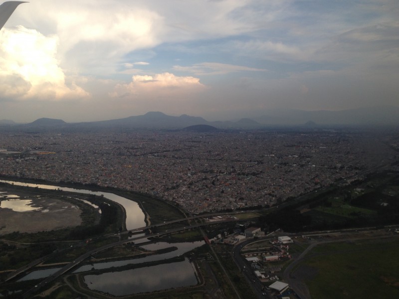 Flying over Mexico City, mountains, sun, buildings