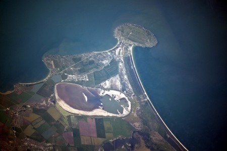 Cape Kazantip is a prominent headland on the Kerch Peninsula, which defines the southern shore of the Sea of Azov and the east extension of the Crimean Peninsula. During the Second World War, German and Soviet forces fought on the Kerch Peninsula, with the line of battle impinging on areas shown at the bottom of the image. The distance from the tip of the Cape to the largest local city, Lenine (population ~70,000, image lower left) is only 20 kilometres.