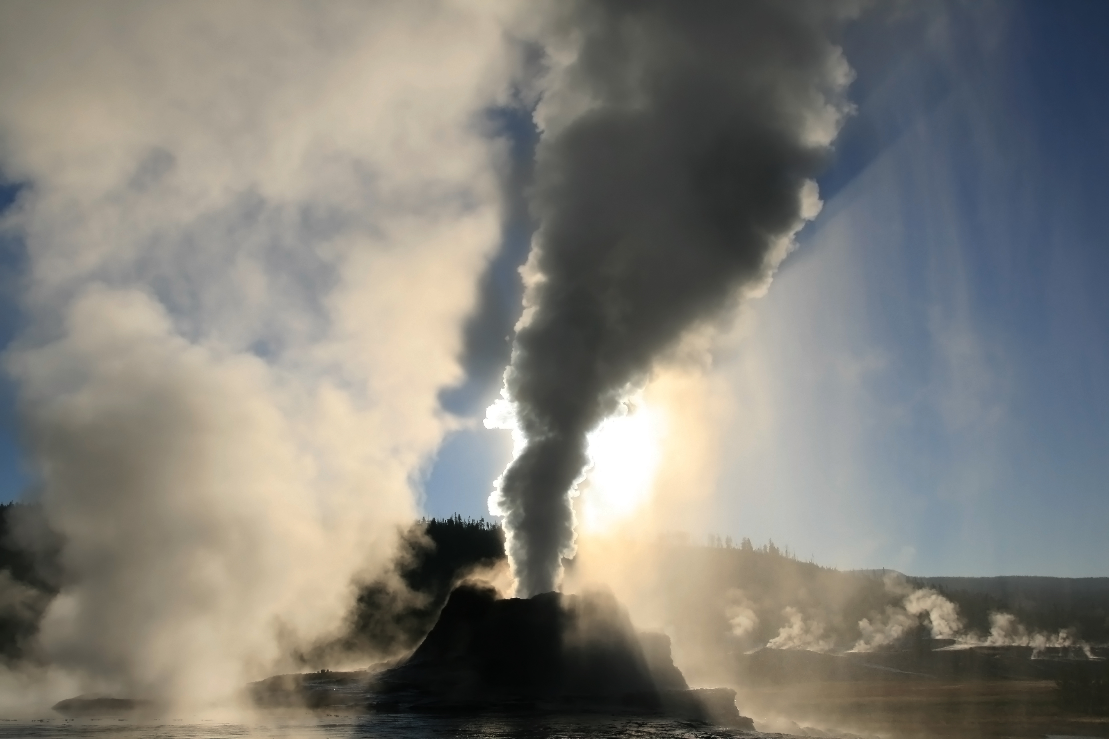 Steam phase eruption of Castle Geyser with crepuscular rays