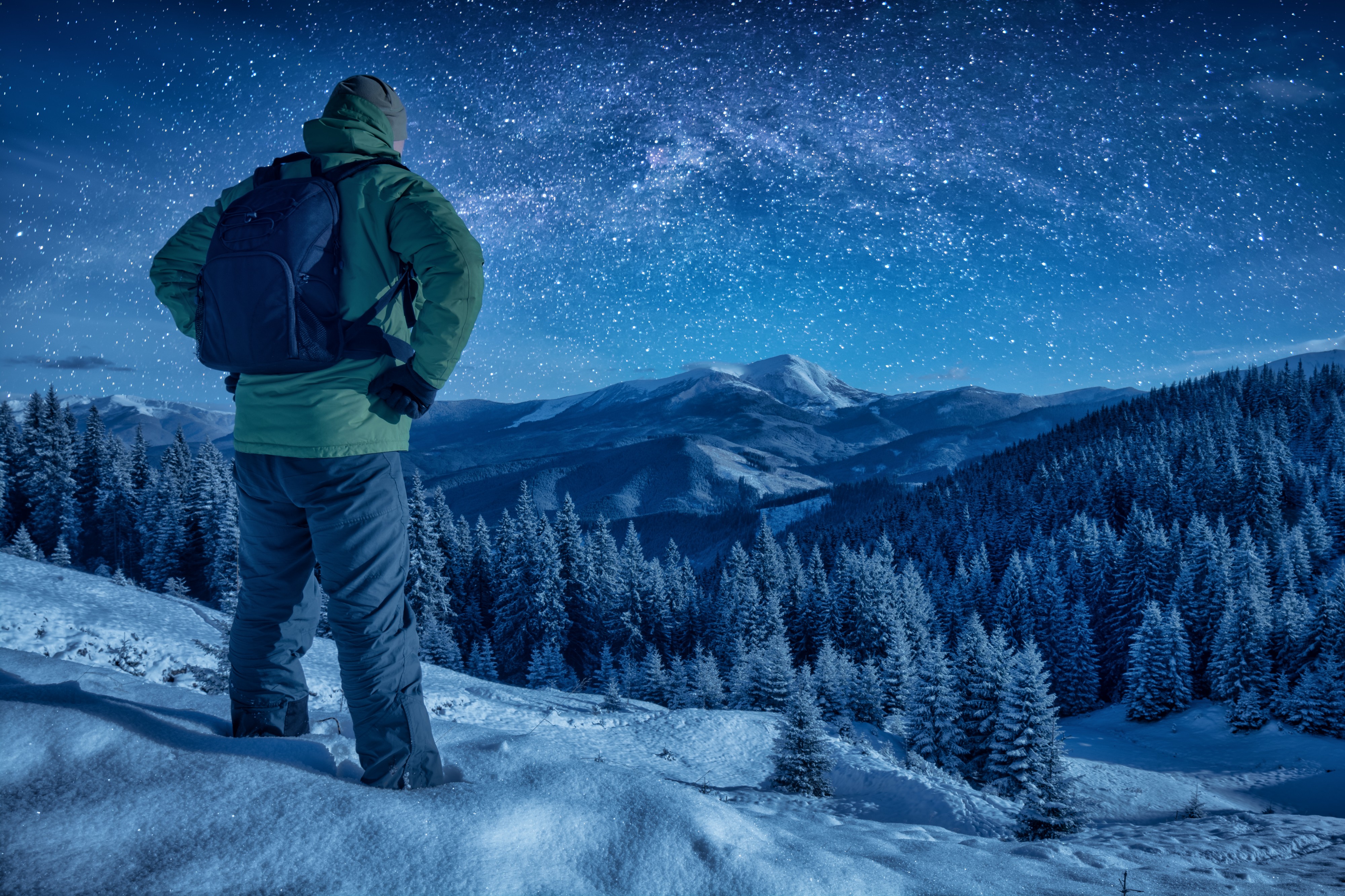 A climber standing on a snowy slope at night