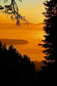 Sunset towards Vancouver, BC as seen from Grouse Mountain. The piece of land in the middle of the picture is home to the University of British Columbia. The mountains in the background are on Vancouver Island.