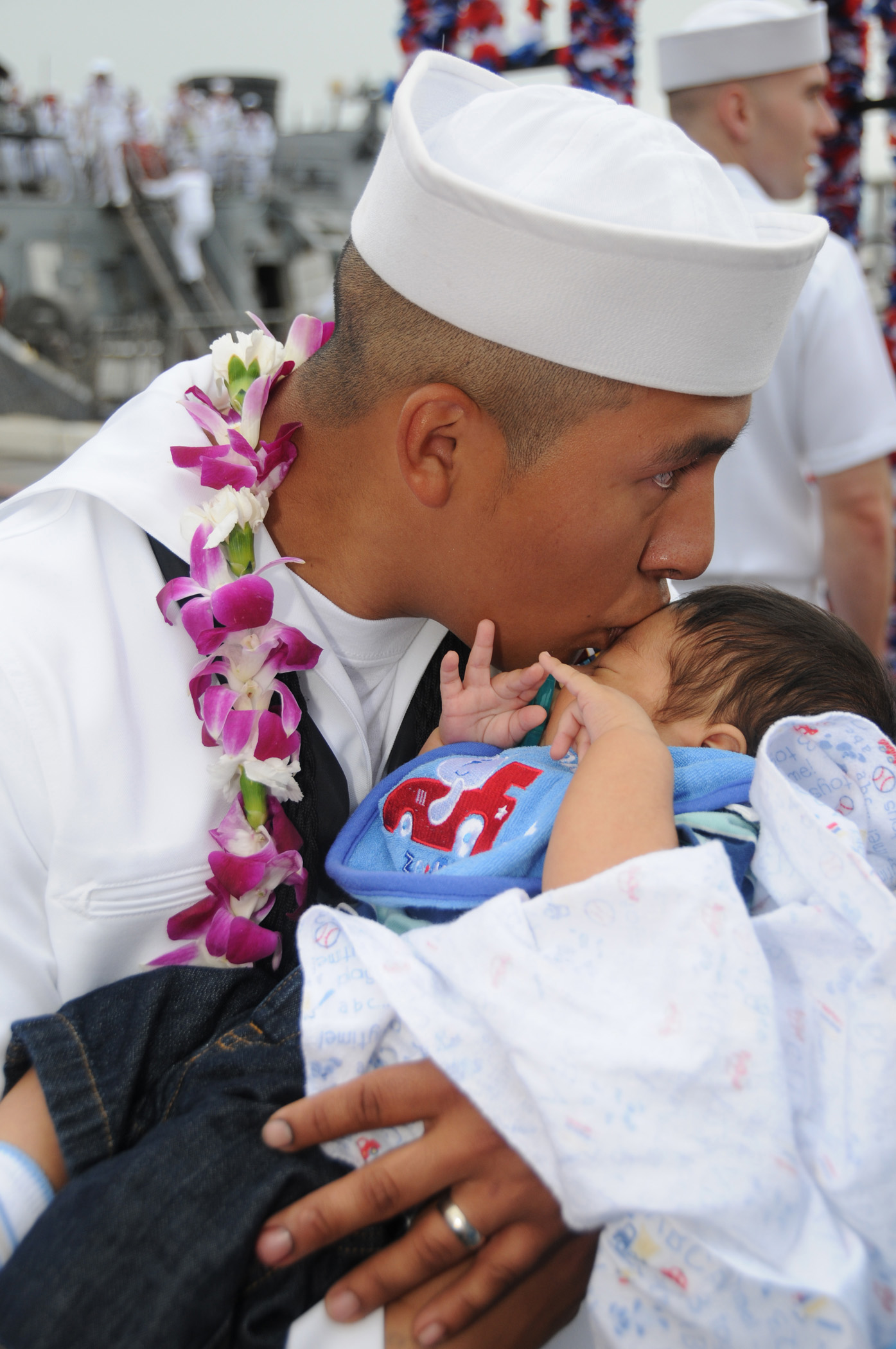 US Navy 090423-N-9758L-256 Boatswain's Mate 2nd Class Roberto Bonilla, assigned to the Arleigh Burke-class guided-missile destroyer USS Hopper (DDG 70), kisses his newborn son after returning from a three-month deployment