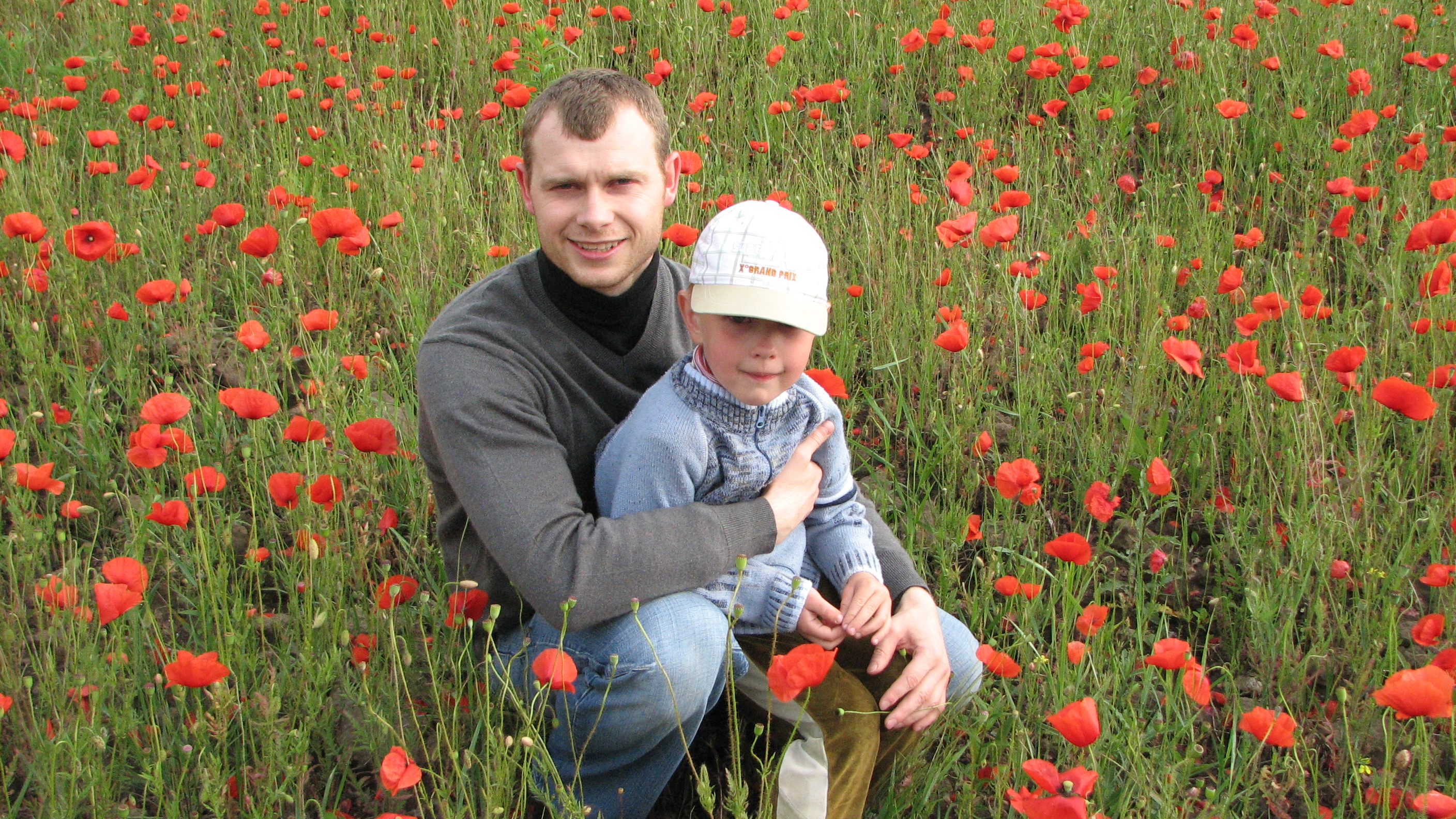 A man with a small boy in a field full of poppies