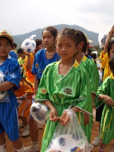A young girl stands among other children at a football match.