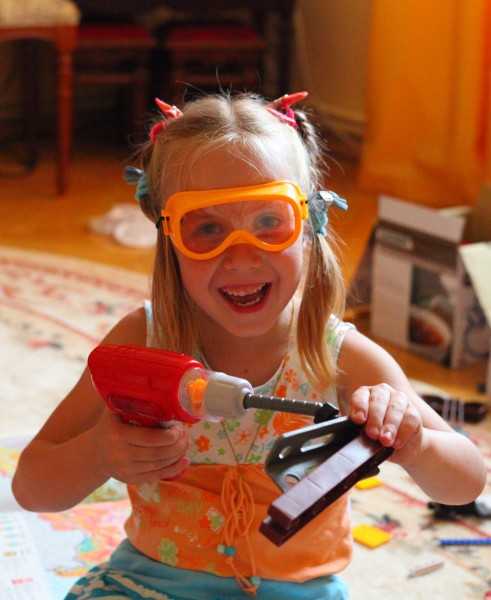 Child girl playing with an electric toy screwdriver