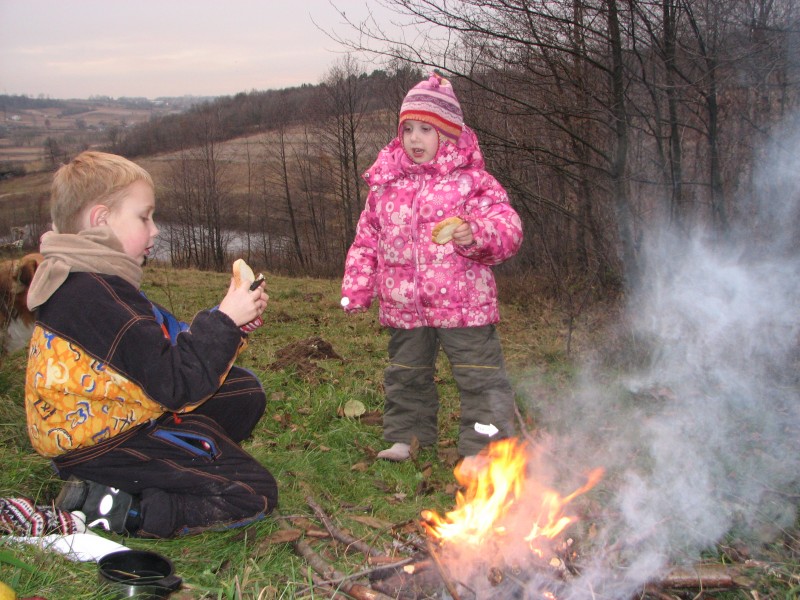 A small boy and a small girl making toasts from bread near fire