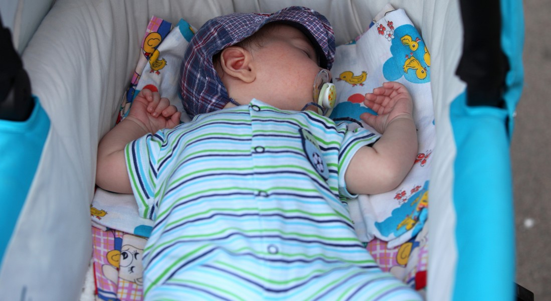 a 2-month old baby boy sleeping in a pram sucking a dummy in July 2013