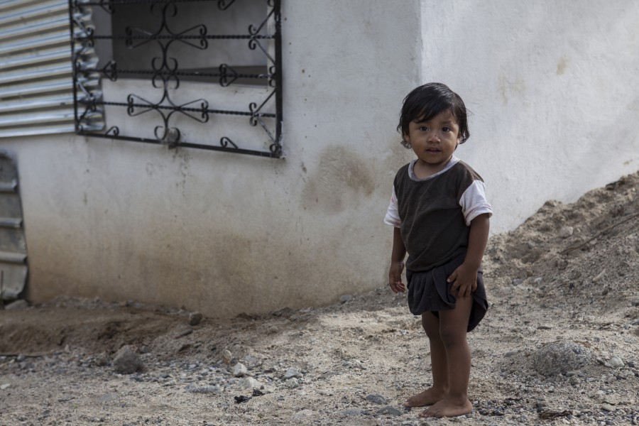 A Guatemalan child stands by his home