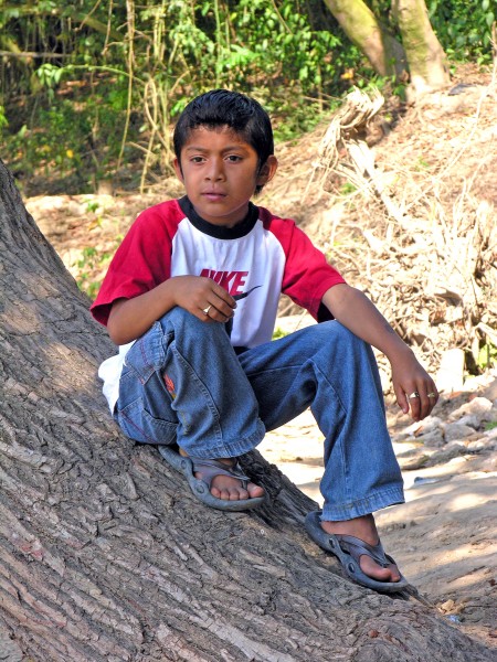 Boy sitting on tree trunk in Guatemala