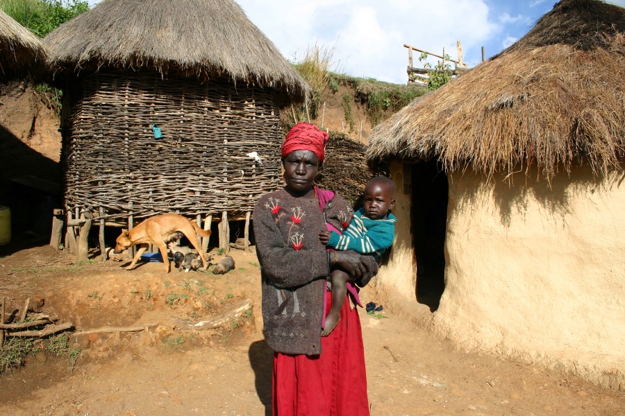 a Marakwet woman holding child in front of her house