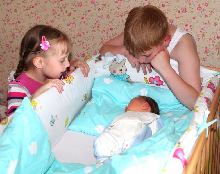 sister and brother happy to meet their newborn brother