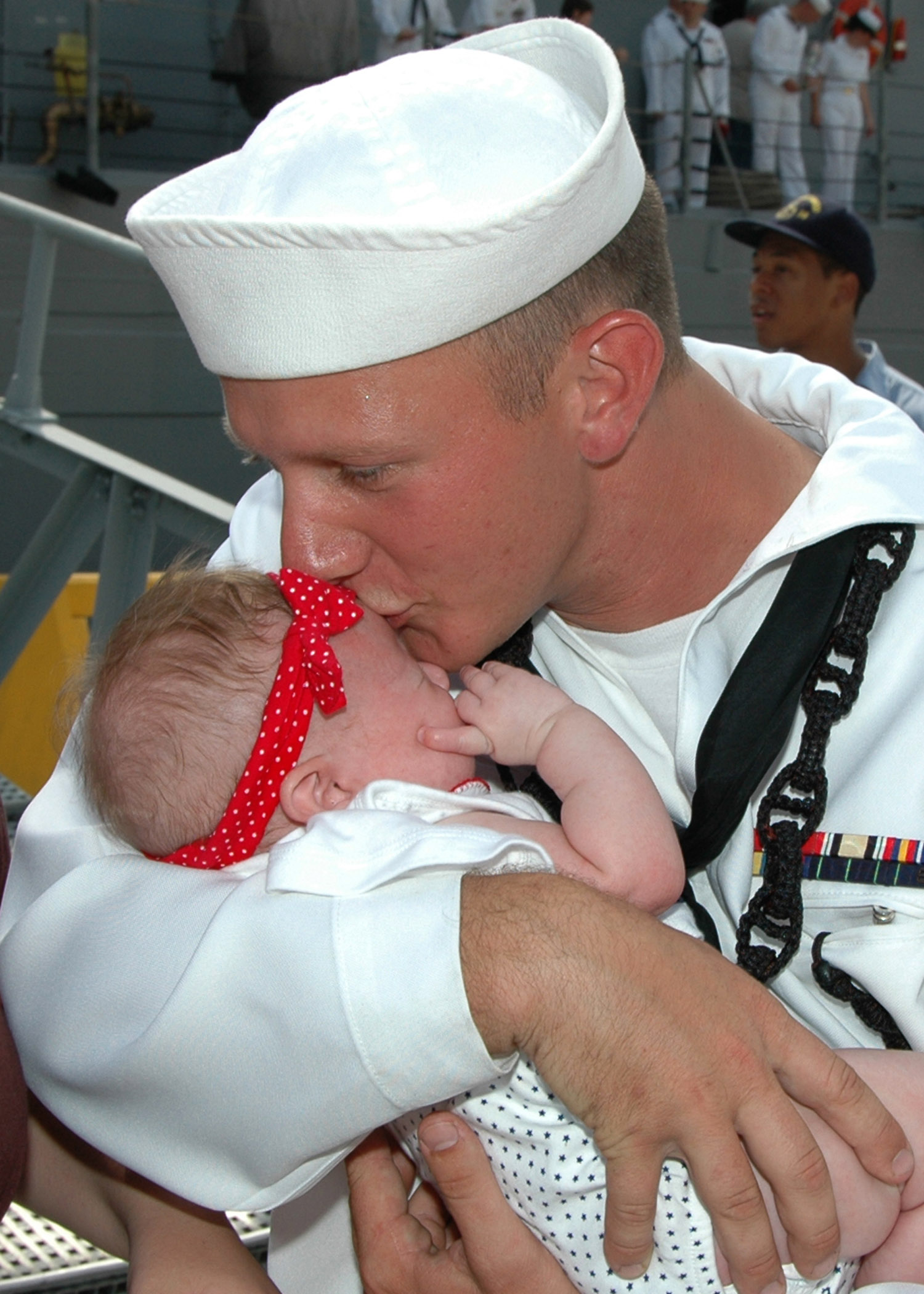 US Navy 070702-N-1522S-075 Boatswain's Mate 3rd Class Christopher Ball kisses his newborn baby, Chloe, for the first time during the homecoming of guided missile frigate USS Underwood (FFG-36)