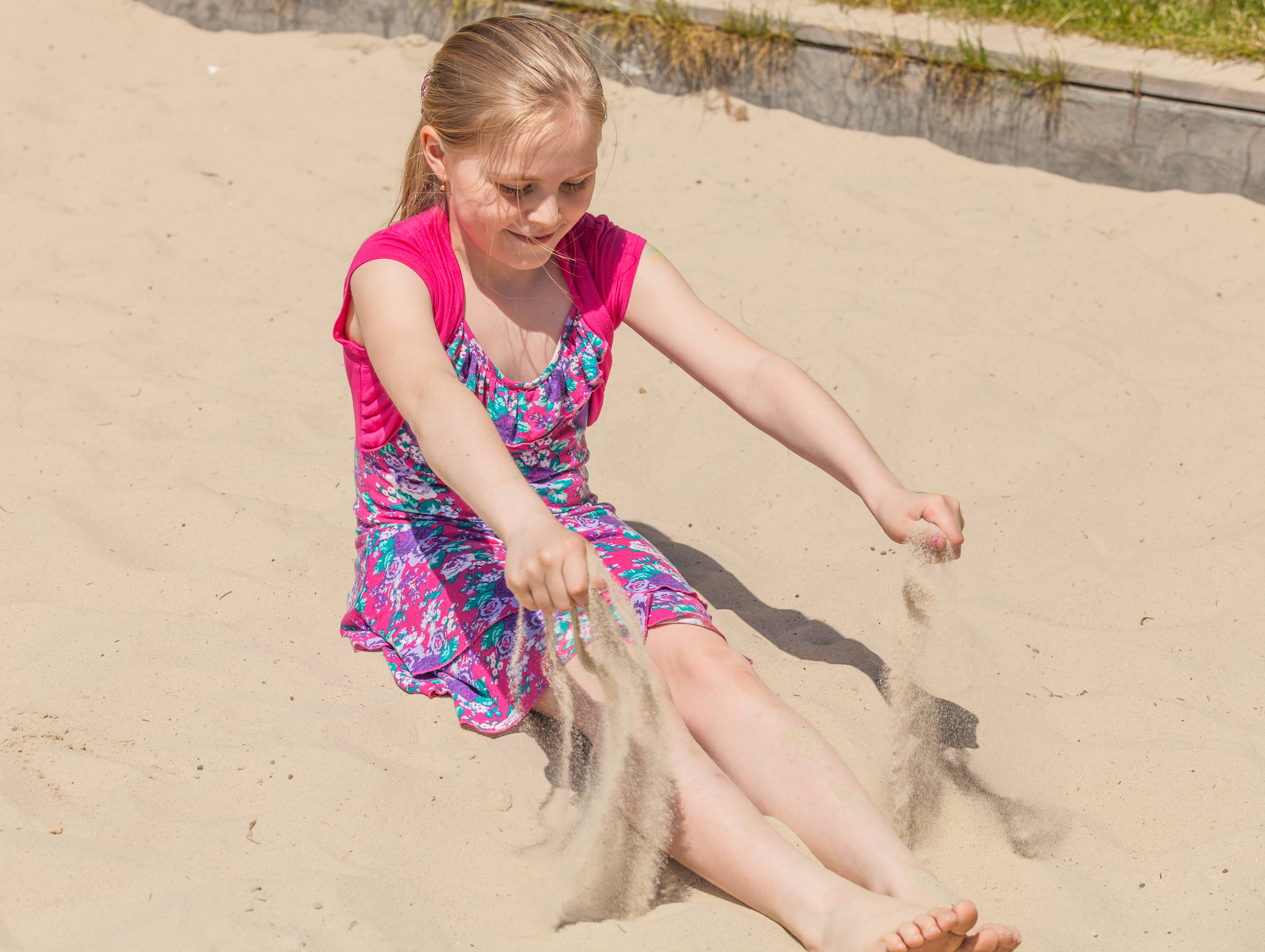 a young Catholic blond girl playing in a sandbox in May 2014, picture 1/3