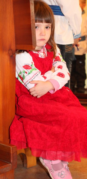 a beautiful amazing cute charming Catholic child girl in a red dress in a Church looks sad, photo 5