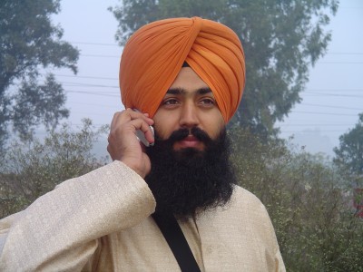 Sikh wearing turban and holding a mobile phone to his ear.