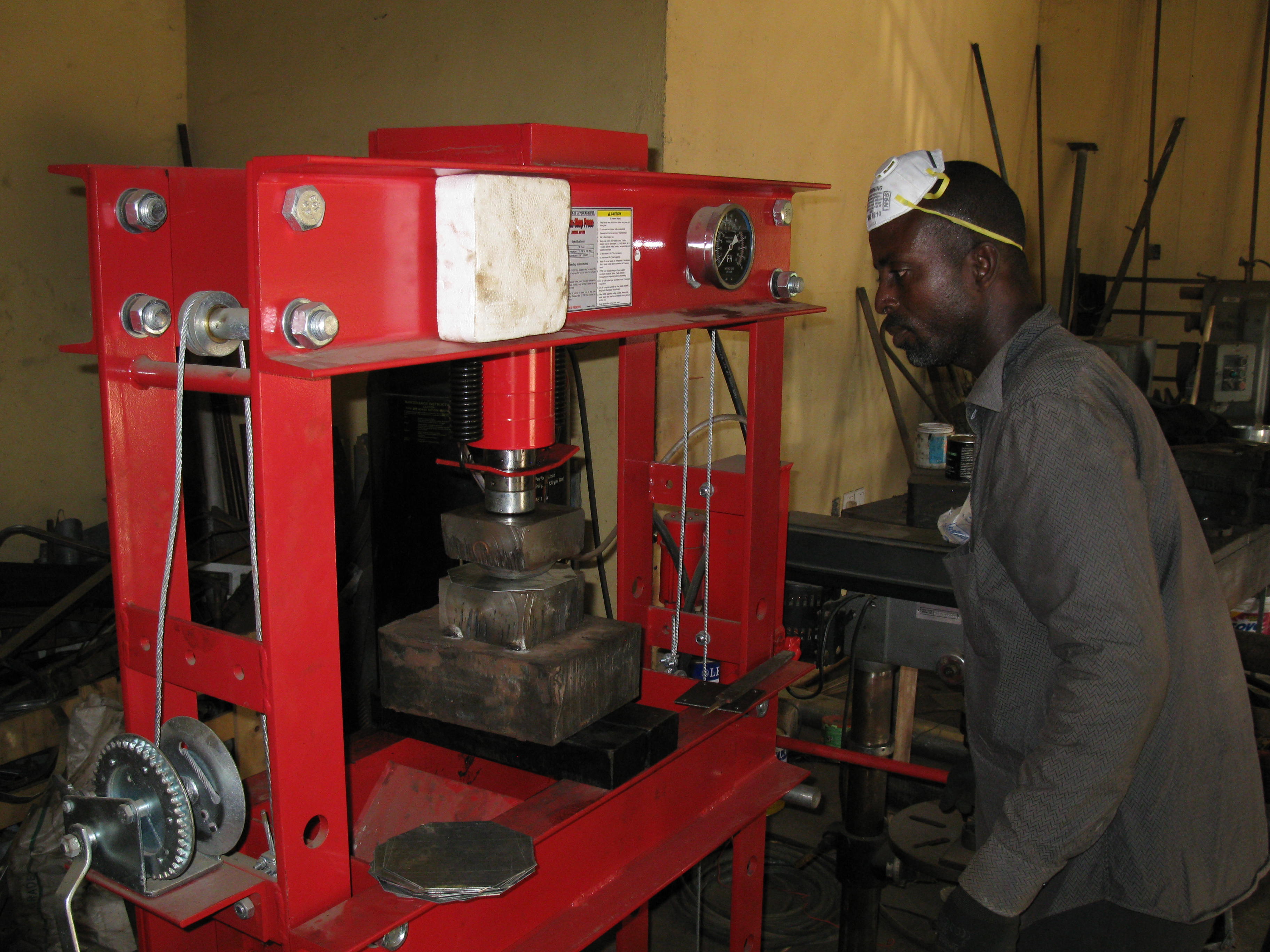 A Ghanaian Metal Fabricator mouds a plate