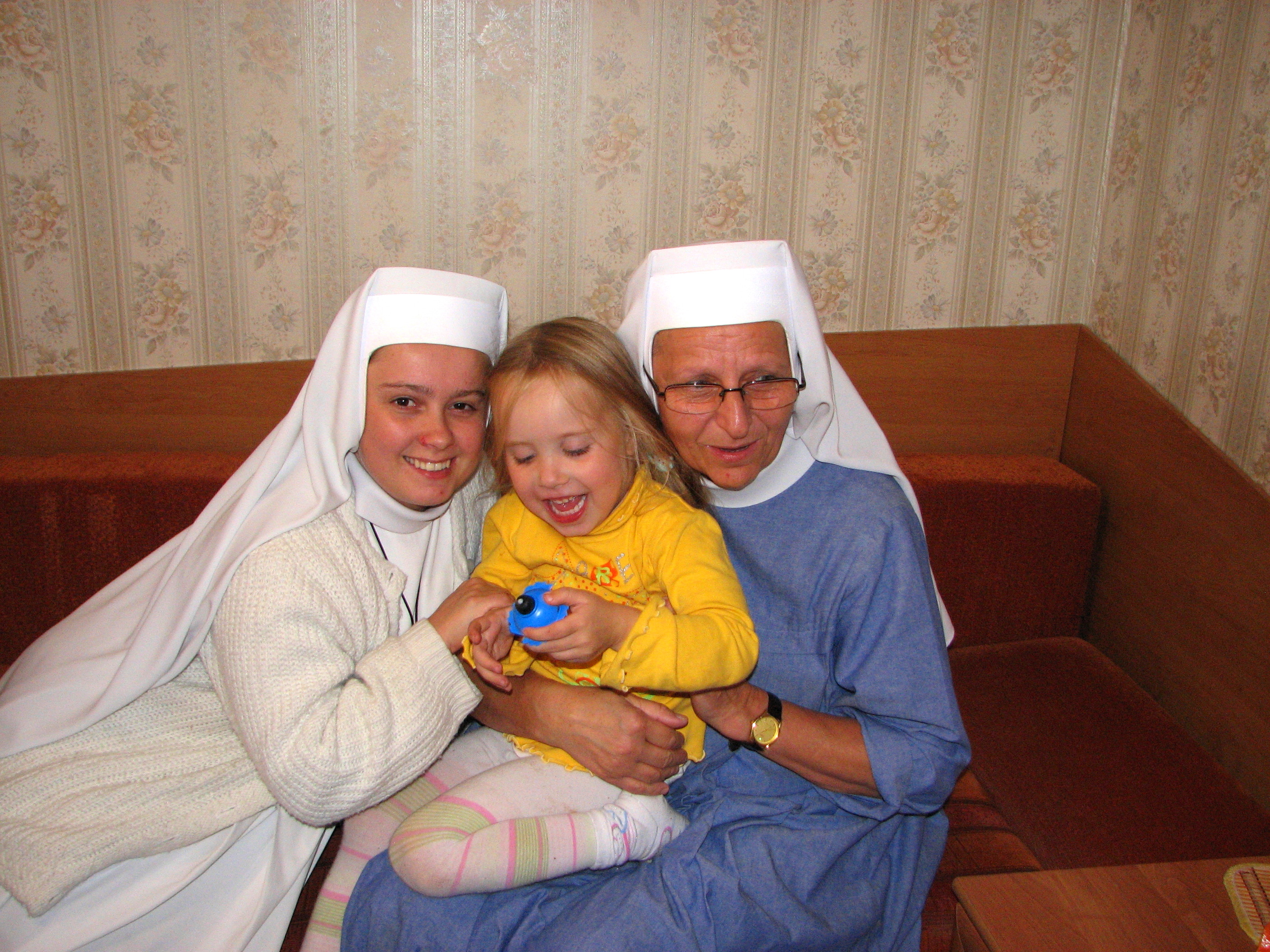 Two Catholic nuns playing with a small child girl, picture 2