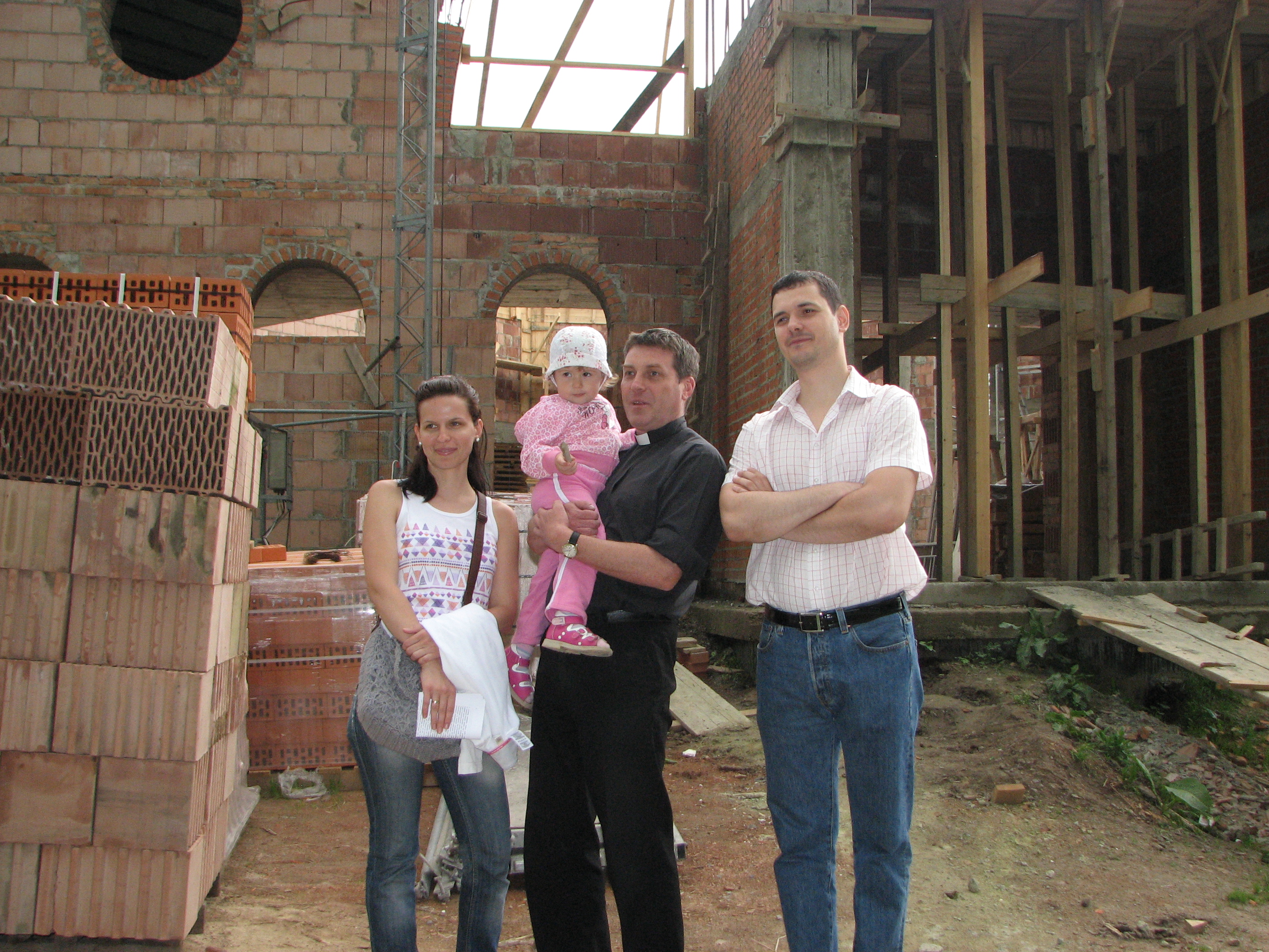A Catholic priest (in the middle) with a young family near a Church which is being built, pic 2