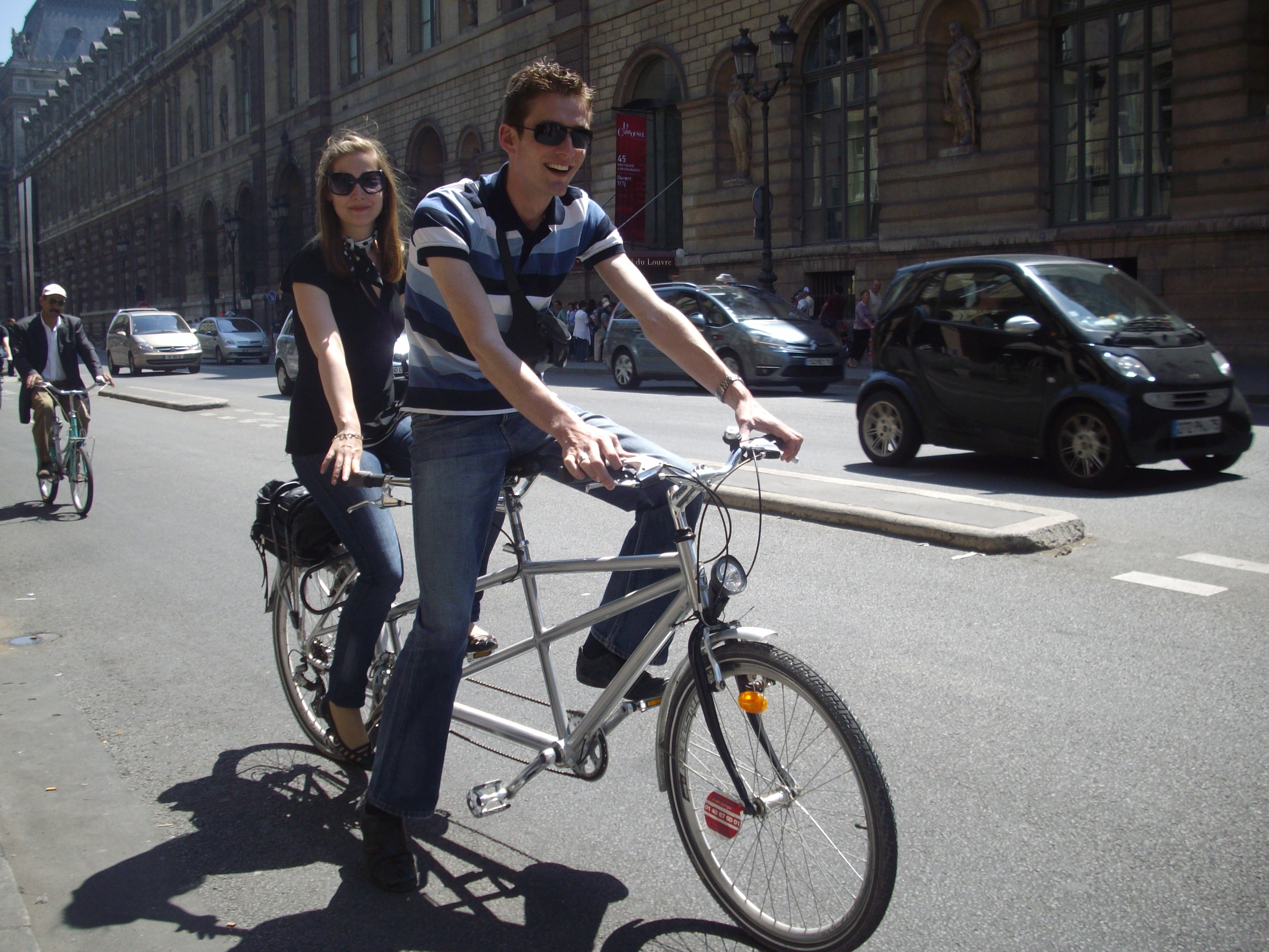 A couple bicycling on the streets of Paris near the Louvre Museum