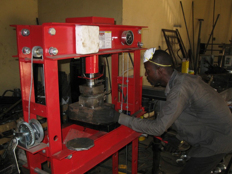 A Ghanaian Metal Fabricator at the hydraulic press