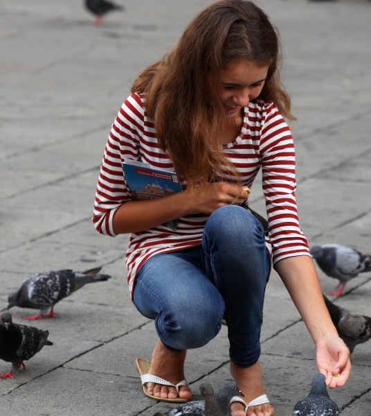 a girl happy to feed pigeons in Padua, Italy, in August 2013