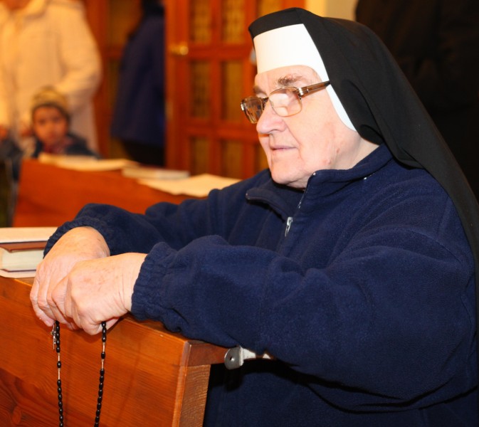 a Catholic nun praying rosary in a Church