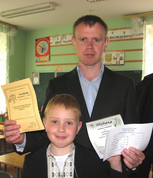 Father and son, with son's school achievement documents. 