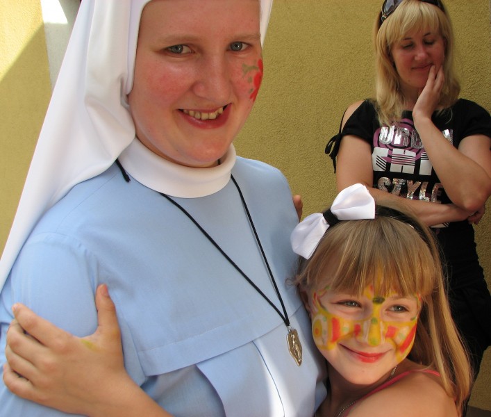 A Catholic nun with a child girl with her mother on the background.