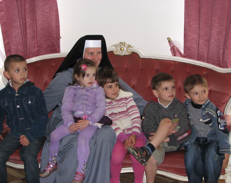 A nun with five children on a sofa