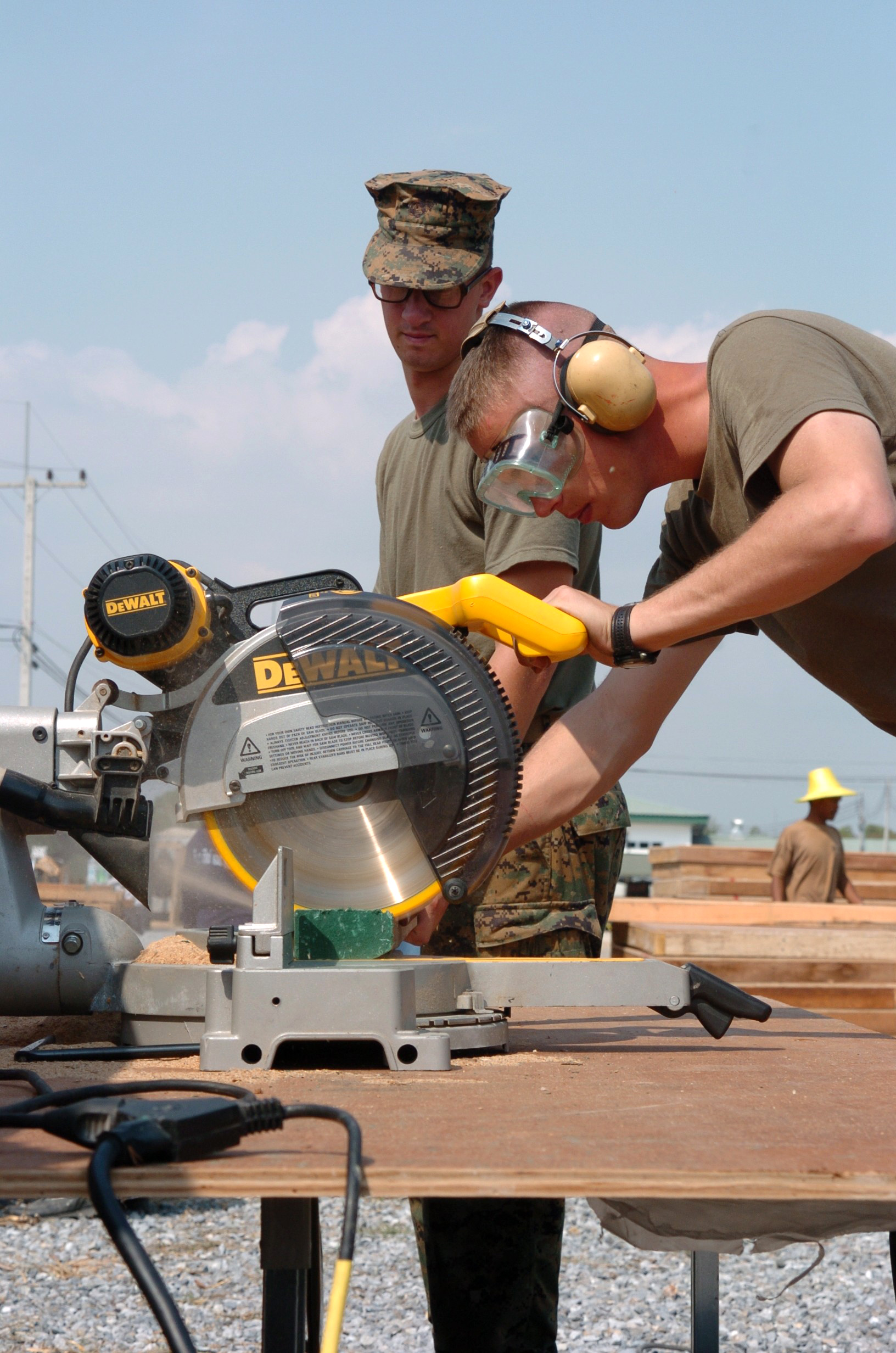 US Navy 050111-M-3295H-006 Lance Cpl. Kevin Shepard, foreground, and Pfc. Anthony Nichols, both assigned to the 3rd Marine Expeditionary Force (MEF), use a radial saw to cut plywood