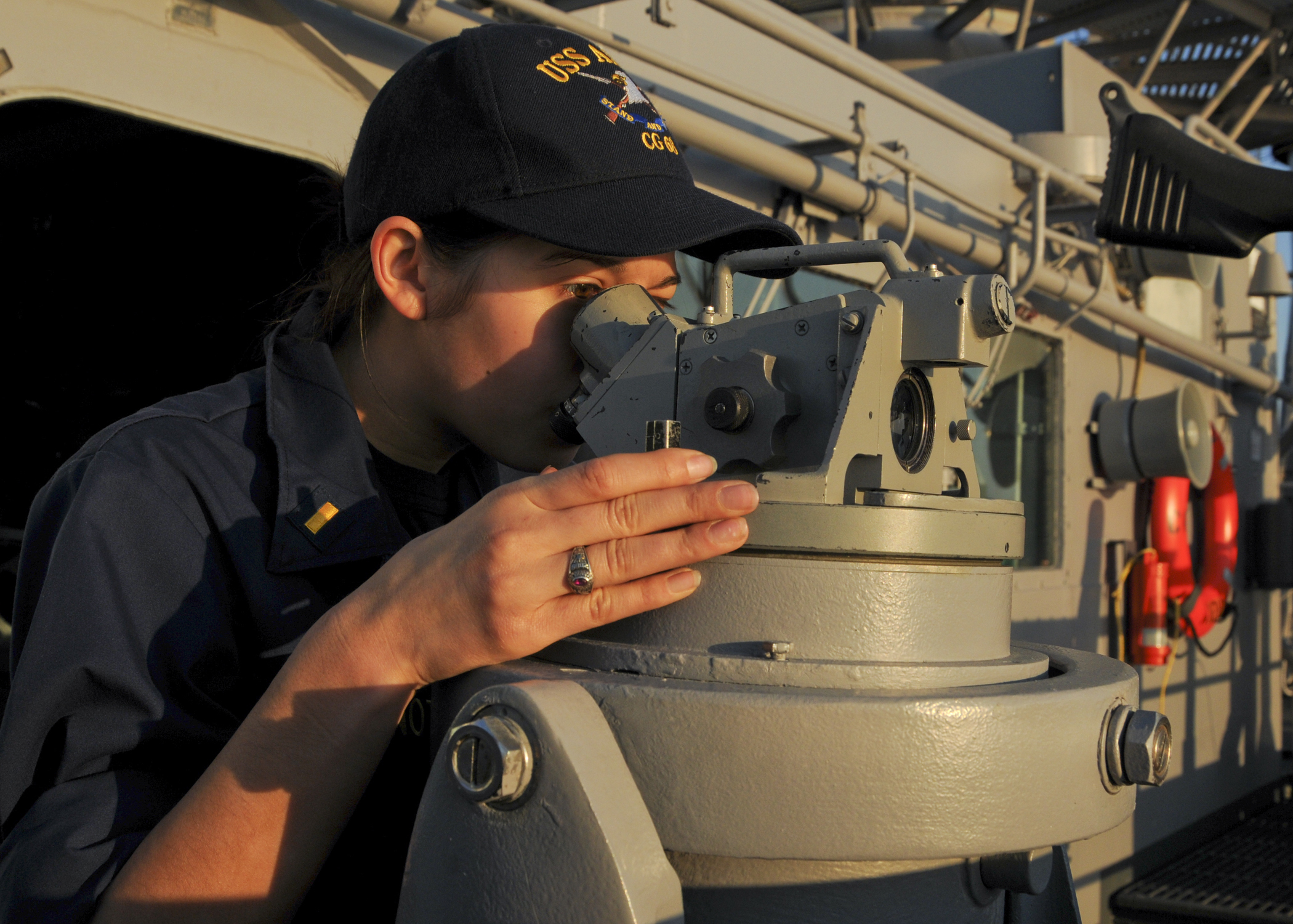 US Navy 110220-N-9793B-005 Ensign Leah M. Fontenot looks through a telescopic alidade on the ship's port bridge wing aboard the guided-missile crui