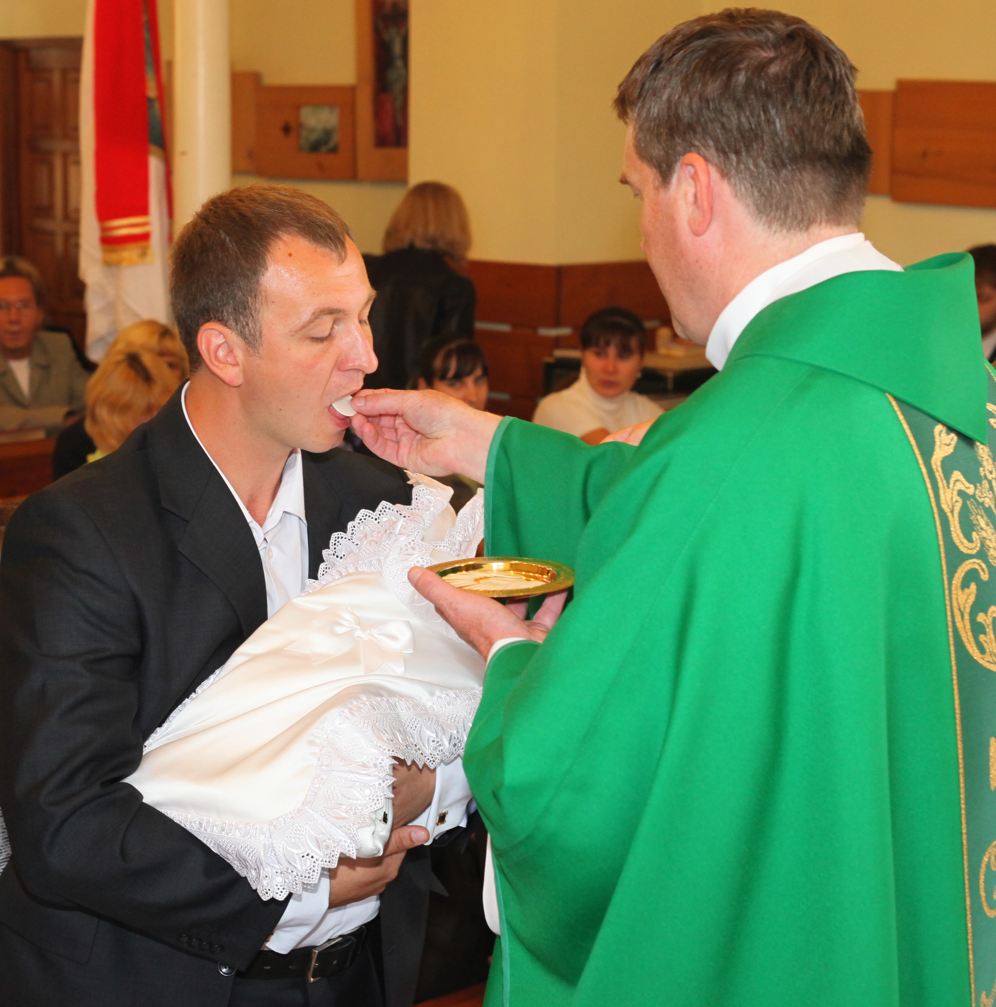 father of the baby-boy is accepting Jesus Christ in the Holy Communion