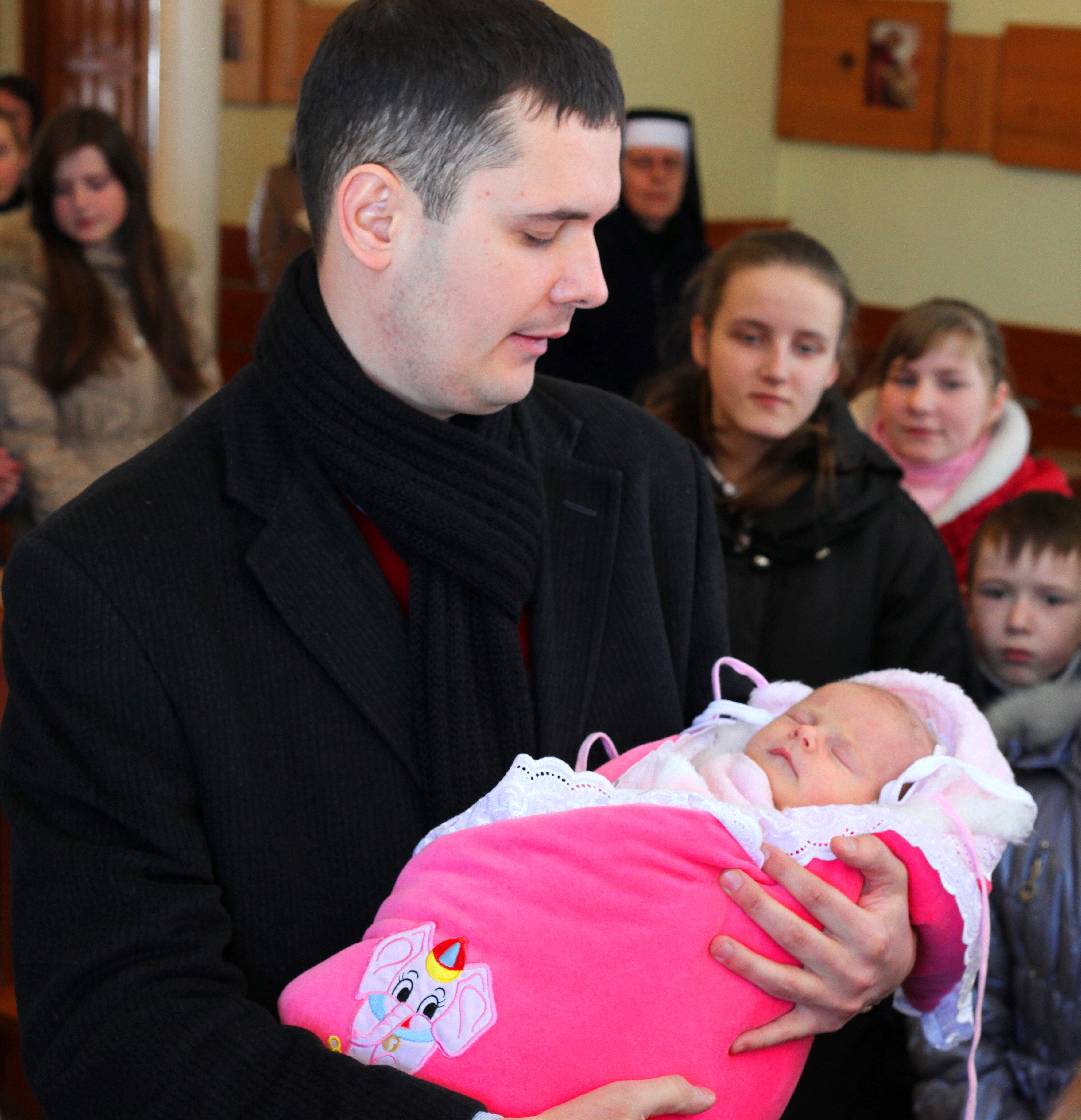 a father holding his baby daughter during her christening in a Catholic Church, photo 2