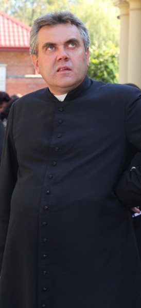 a Catholic priest near a Church looking upward