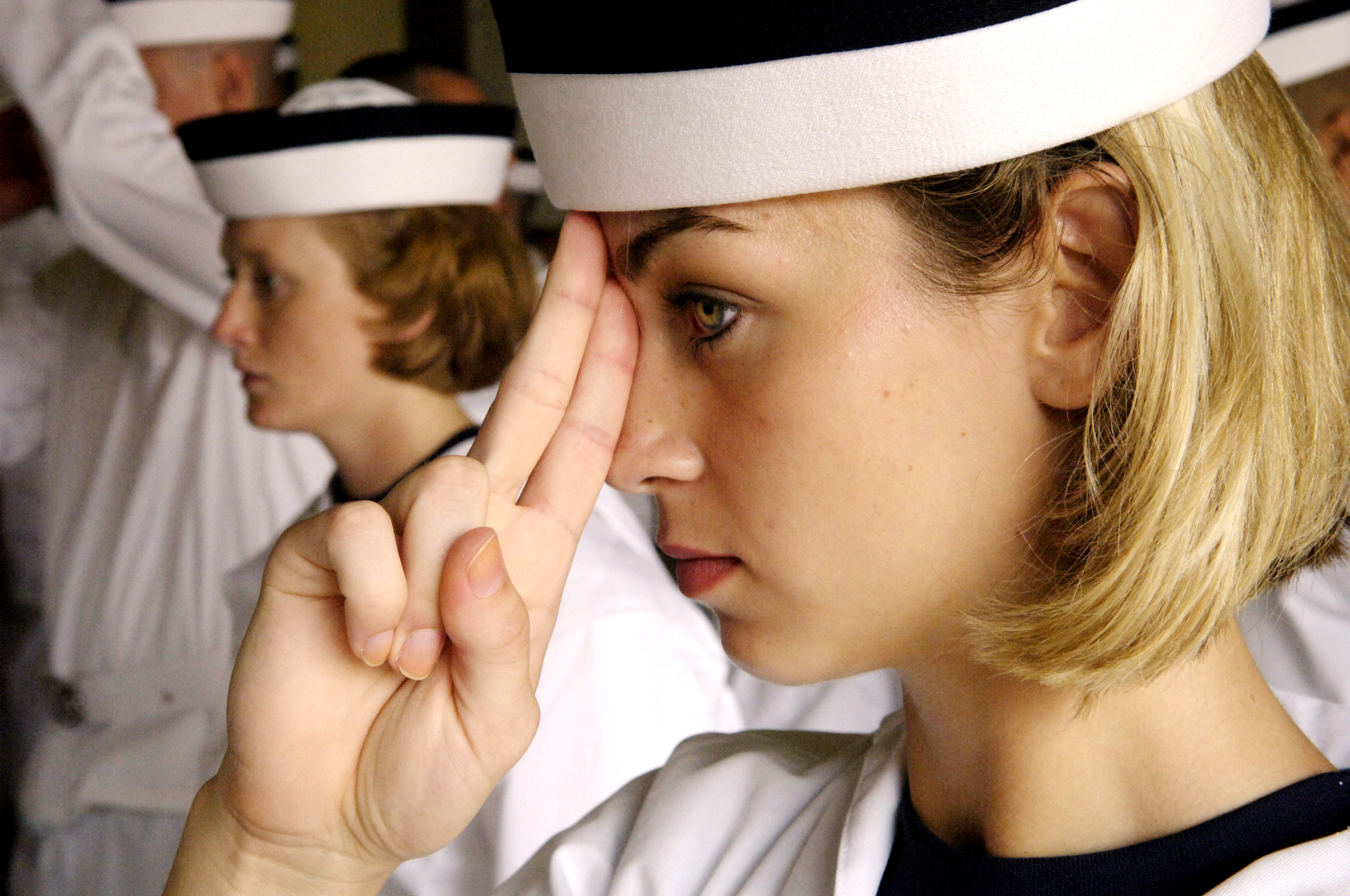 US Navy 070627-N-9241M-130 Ashley Bucholz is taught how to properly wear her cover. The cover should rest two fingers above the top of her nose