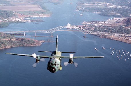 A front view of a C-27A Spartan in flight over a bridge and water. Location: HOWARD AIR FORCE BASE