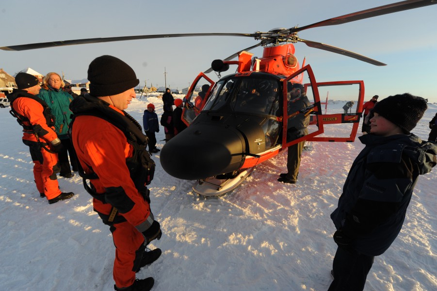 U.S. Coast Guard Petty Officer 2nd Class Chad Griffin, an aviation mechanic, speaks to a Nome, Alaska, resident about working aboard a Coast Guard MH-65 Dolphin helicopter in Nome Jan 120118-G-YE680-099