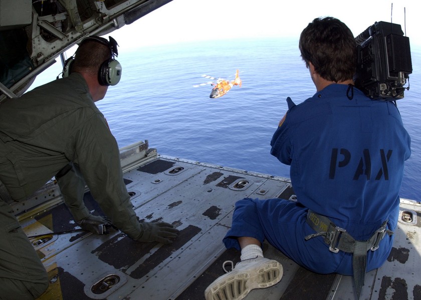 US Navy 021220-N-7590D-025 U.S. Coast Guard air crewman looks on as Bill Paris, a commercial cameraman captures footage of an HH-65A Helicopter