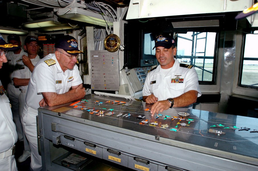 US Navy 040505-N-6213R-028 Adm. Vern Clark, Chief of Naval Operations (CNO), looks on as Lt.j.g. David Martinez demonstrates flight deck operating procedures in Flight Deck Control