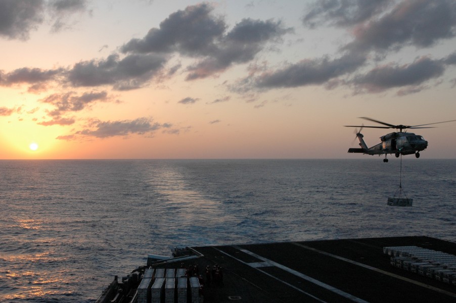 US Navy 070405-N-1635S-006 With the sun setting behind the aircraft carrier USS Ronald Reagan (CVN 76), an HH-60H Seahawk