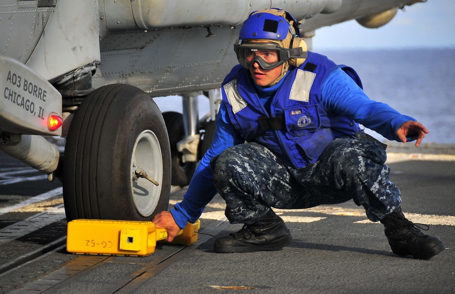 US Navy 100406-N-4774B-604 Boatswain's Mate Seaman Apprentice Anthony Orduna prepares to remove a chock from the landing gear of an SH-60F Sea Hawk helicopter