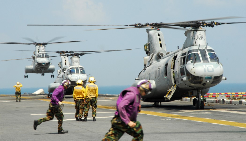 US Navy 110213-N-8607R-393 Aviation fuel crew members run to fuel a CH-46E Sea Knight helicopter aboard the forward-deployed amphibious assault shi