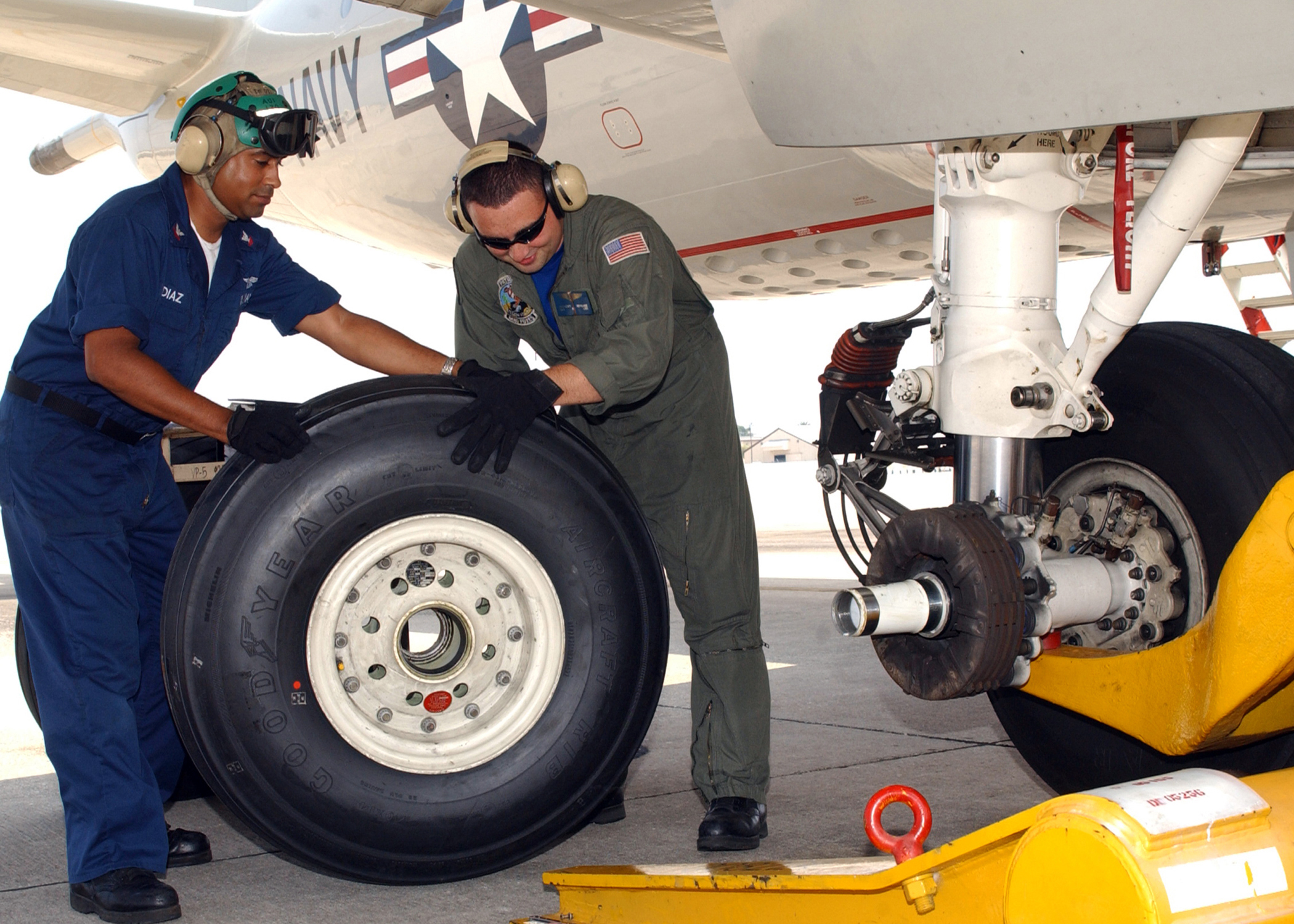 Two man replace a main landing gear tire of a plane