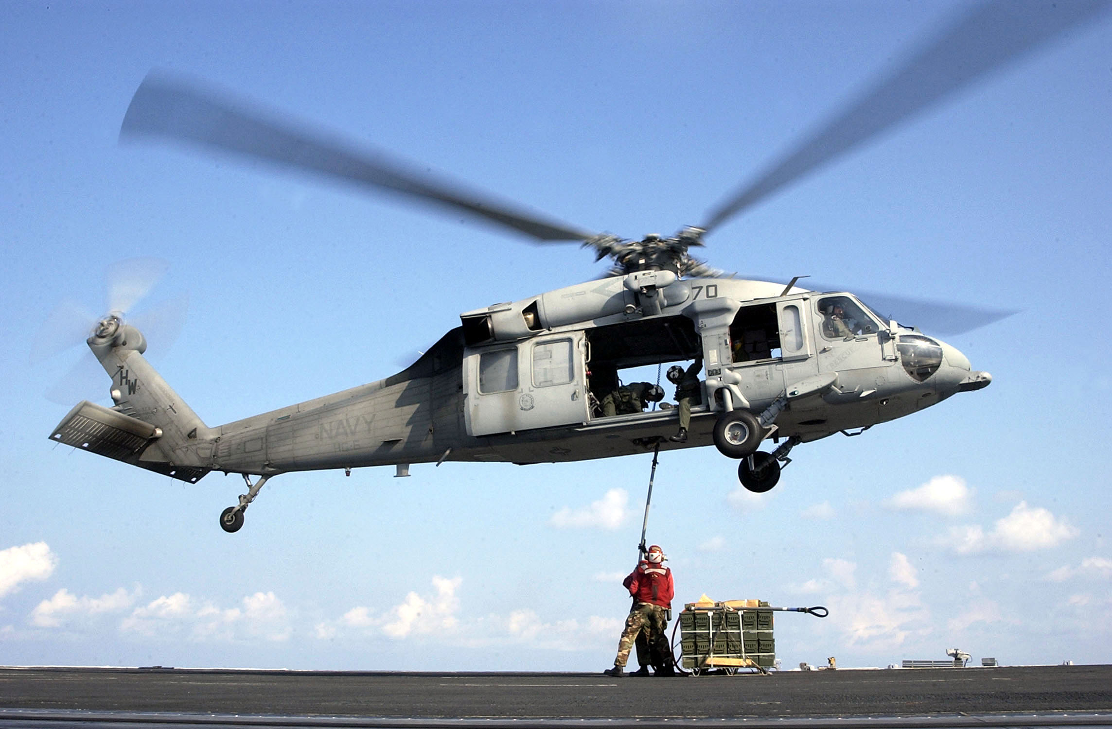 US Navy 030721-N-4308O-012 Aviation Ordnanceman attach a replenishment sling containing ordnance to an MH-60S Knighthawk